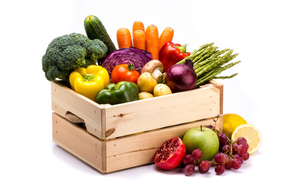 Pine box full of colorful fresh vegetables and fruits on a white background